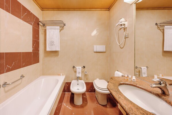 Un baño con bañera, bidé, inodoro y lavabo.