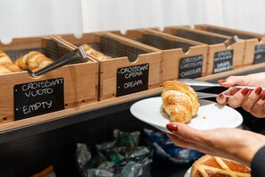 A bakery display with labeled compartments for croissants and cream, and a person holding a croissant.