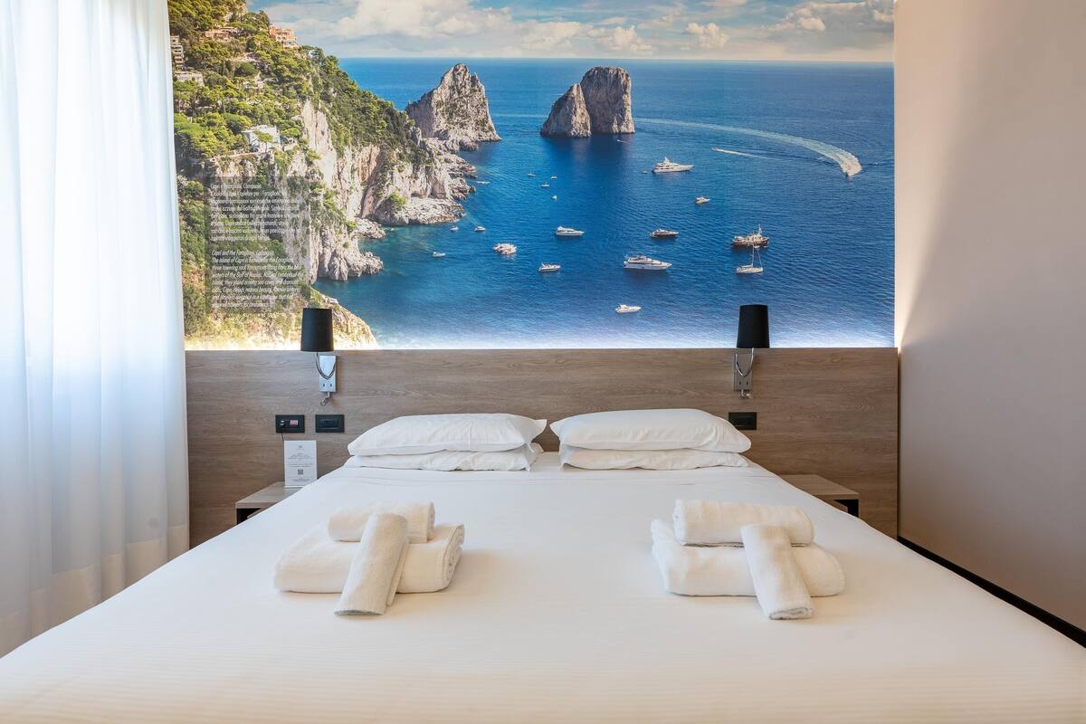 A hotel room with a large bed, two white pillows, and neatly folded towels.