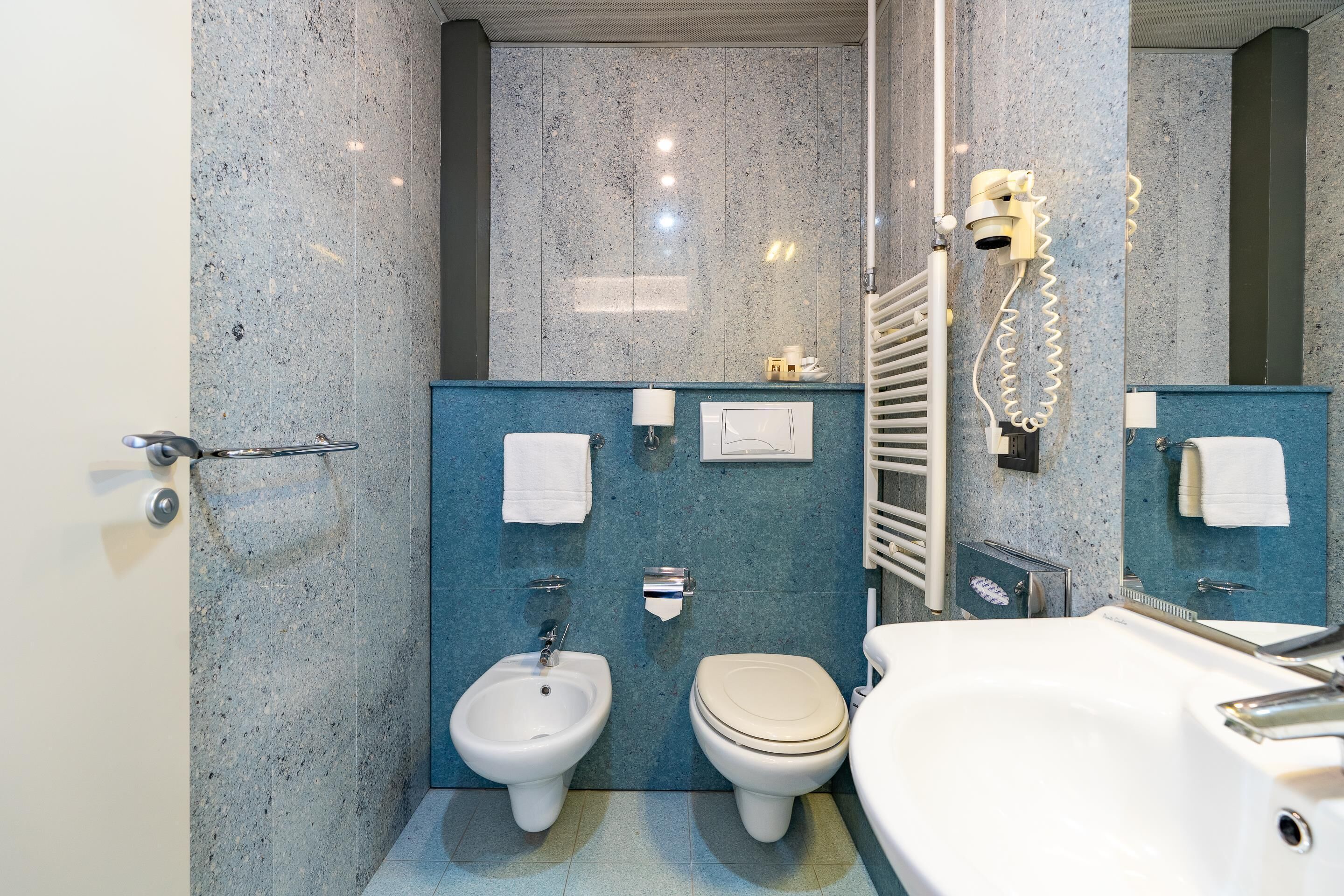 A modern bathroom with a bidet, toilet, and bathtub.