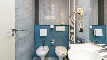 A modern bathroom with a bidet, toilet, and bathtub.