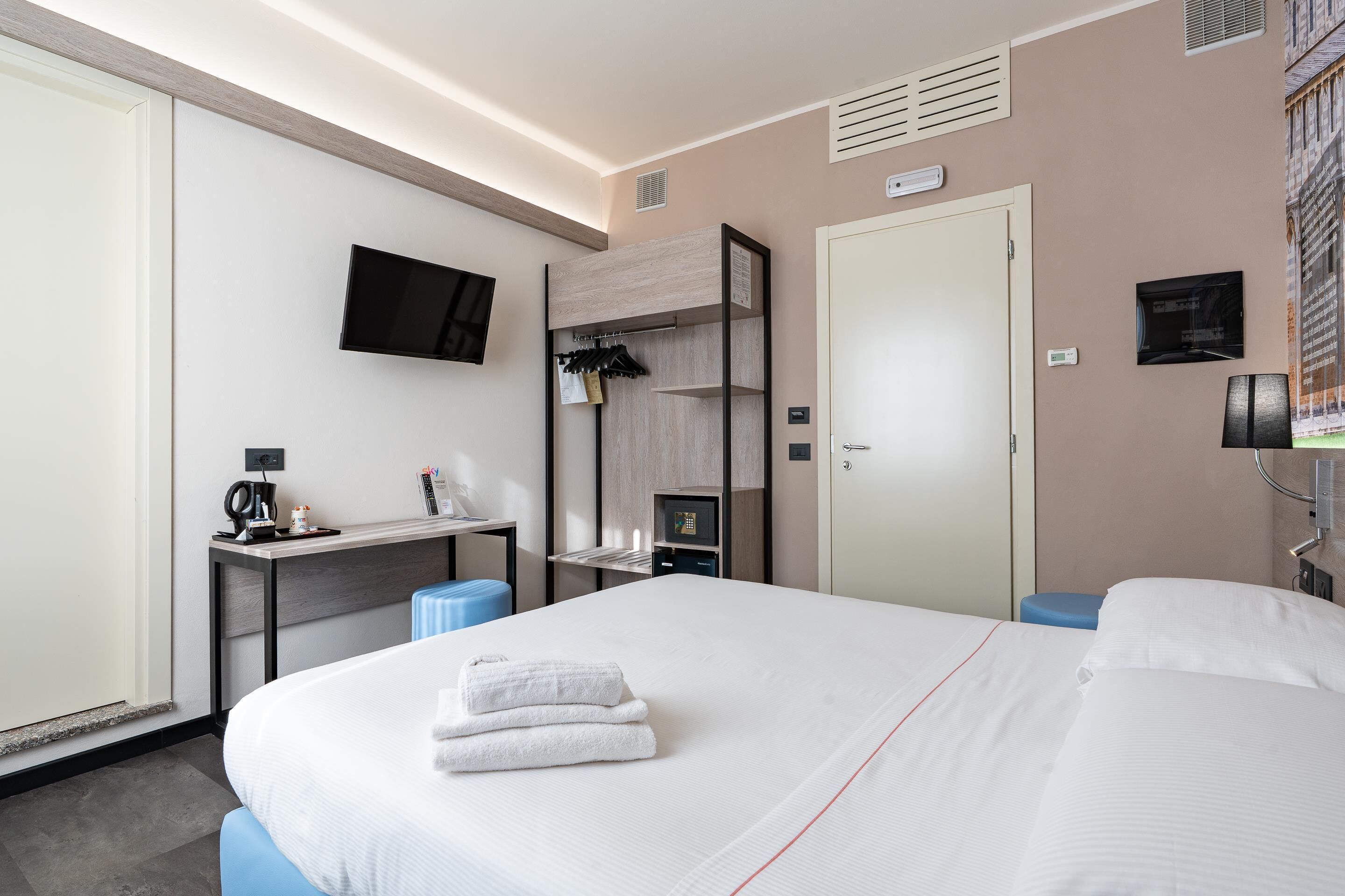 Una habitación de hotel con una cama, un escritorio, un televisor y un armario.