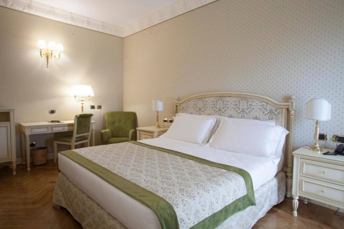 A neatly arranged bedroom with a large bed, a desk, and two chairs.