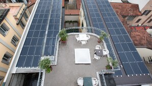 A rooftop terrace with solar panels, outdoor seating, and potted plants.