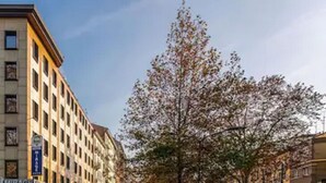 A multi-story building with a corner entrance, a visible garage sign, and a tree with sparse leaves. - Hotel Mirage, Sure Hotel Collection by Best Western (Milan)