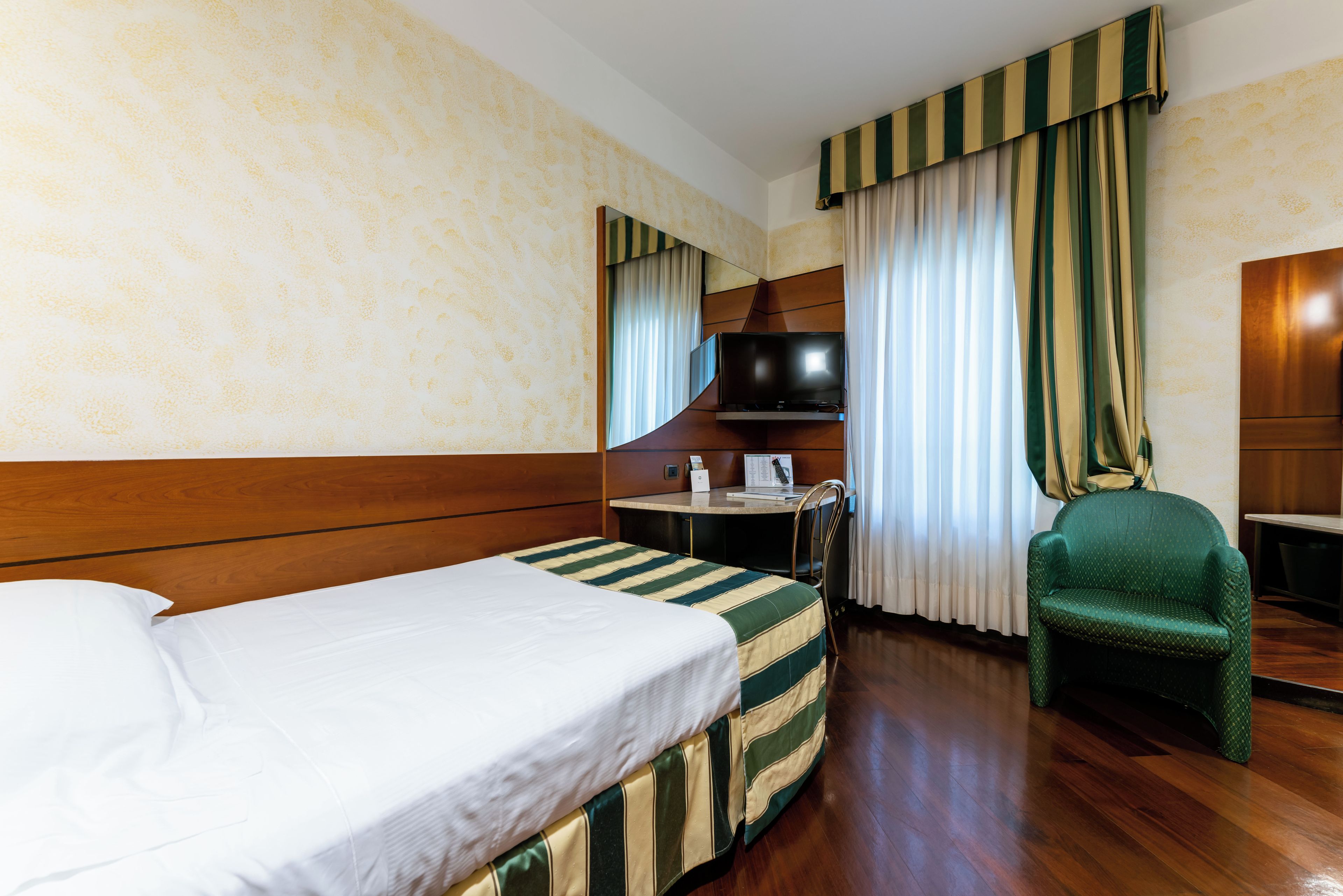 Una habitación de hotel con cama, escritorio, silla y televisor.