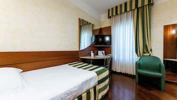 Una habitación de hotel con cama, escritorio, silla y televisor.