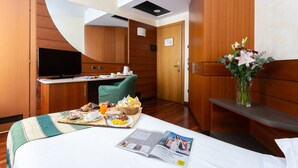 A hotel room with a bed, a dining area with breakfast, a television, and a vase with flowers. - Hotel Mirage, Sure Hotel Collection by Best Western (Milan)