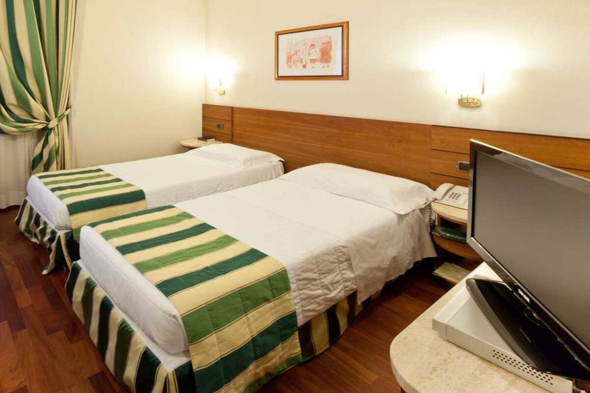 Een hotelkamer met twee bedden, een televisie, een bureau en een stoel.