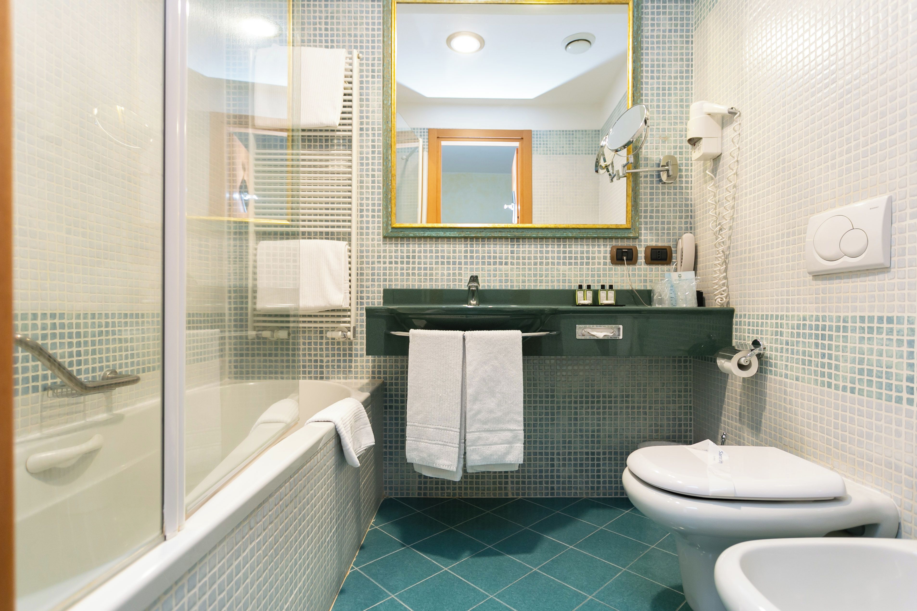 A bathroom with a bathtub, toilet, and sink, featuring a tiled floor and walls.
