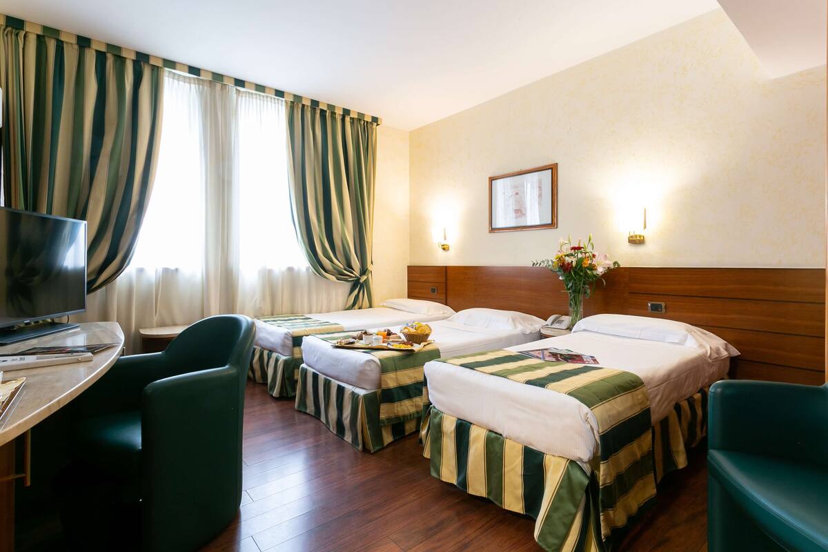 Een hotelkamer met twee éénpersoonsbedden, een televisie, een bureau en een stoel.