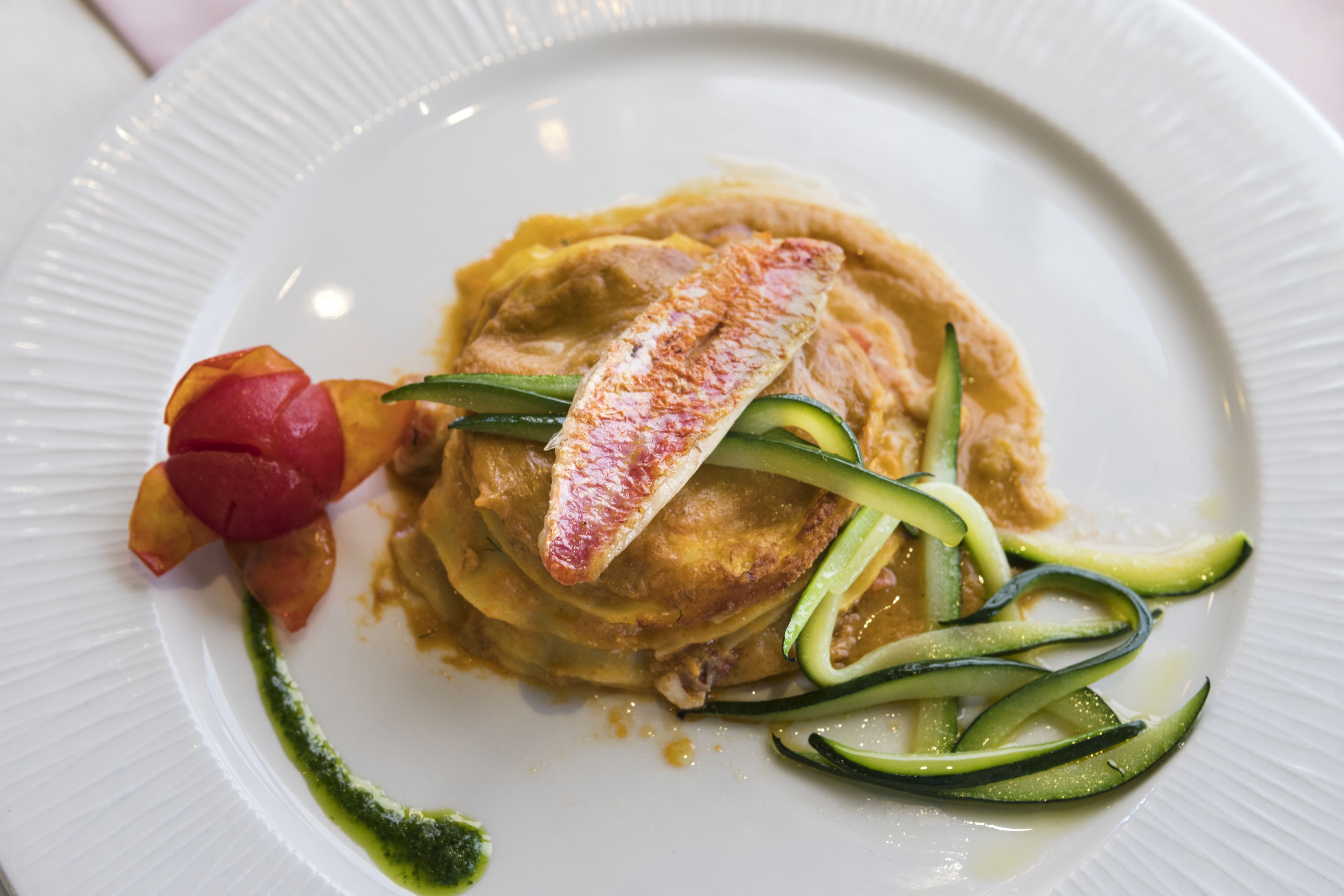 Une assiette contenant une pile de crêpes, un morceau de poisson et quelques légumes.