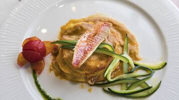 Un plato con una pila de tortitas, un trozo de pescado y algunas verduras.