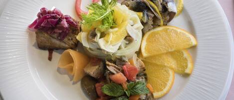A plate of food with various ingredients including fish, vegetables, and garnishes.