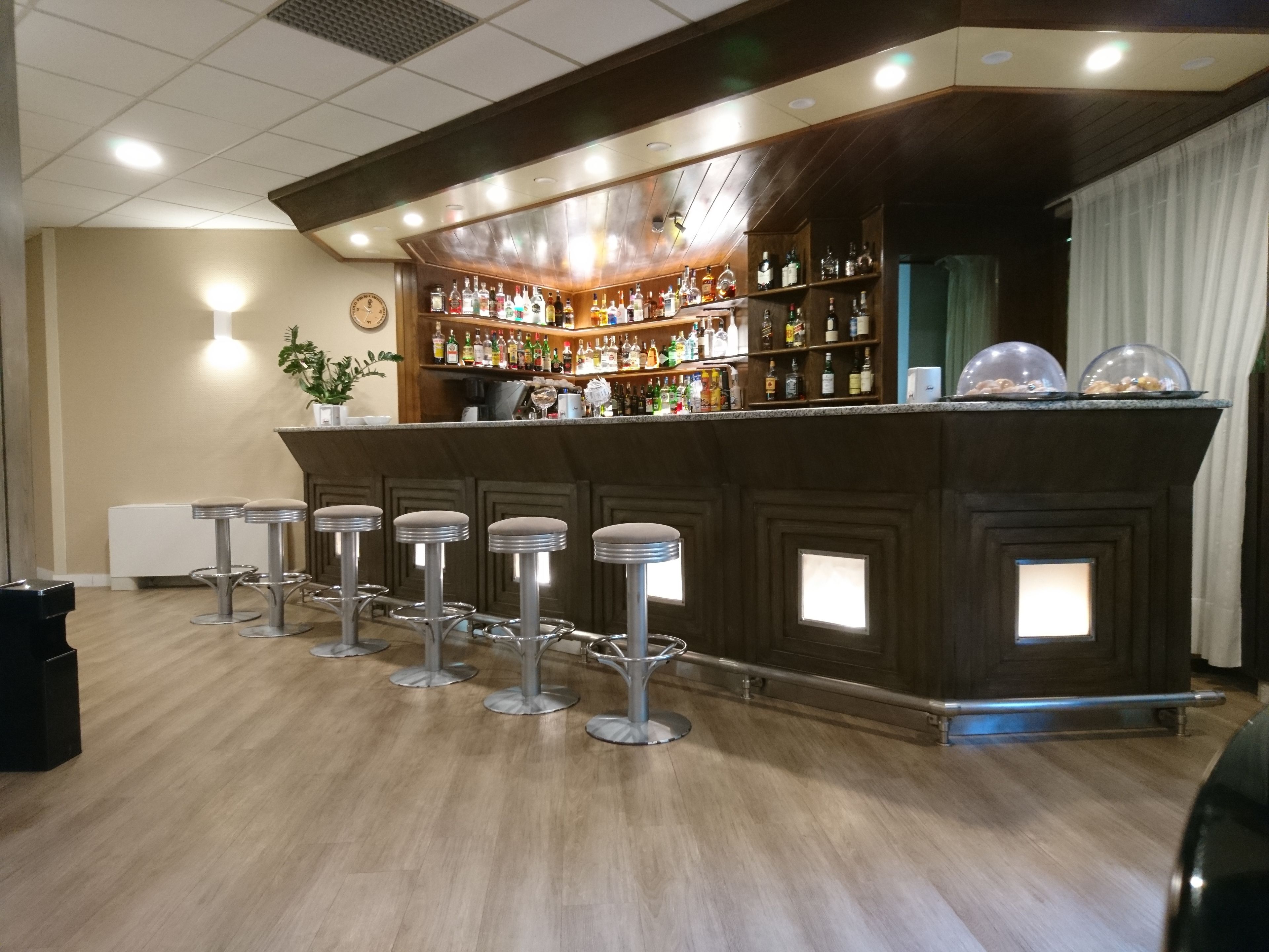 Un espace bar doté d’un comptoir en bois, de plusieurs tabourets et d’une variété de bouteilles.