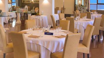 Un ristorante con diversi tavoli apparecchiati per la cena, ognuno completo di sedie e stoviglie.