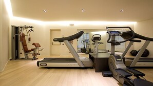 Une salle de sport équipée de tapis de course, de vélos d’appartement et d’un appareil d’aviron.