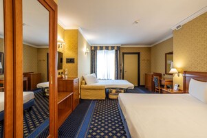 Una habitación de hotel con una cama grande, un escritorio, una silla, un armario y un espejo.