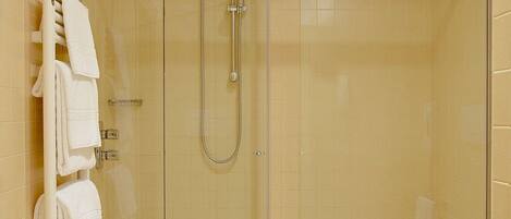 A modern bathroom with a glass-enclosed shower, a white toilet, and a towel rack with neatly folded towels.