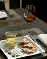 Una mesa con una copa de vino, un plato de pasteles y un tarro de crema.