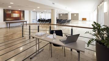 A spacious conference room with a long table, chairs, and a laptop.