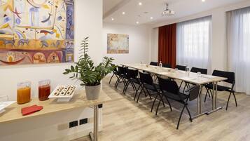 Ein moderner Konferenzraum mit einem langen Tisch, schwarzen Stühlen, einer Zimmerpflanze und abstrakter Kunst an den Wänden.