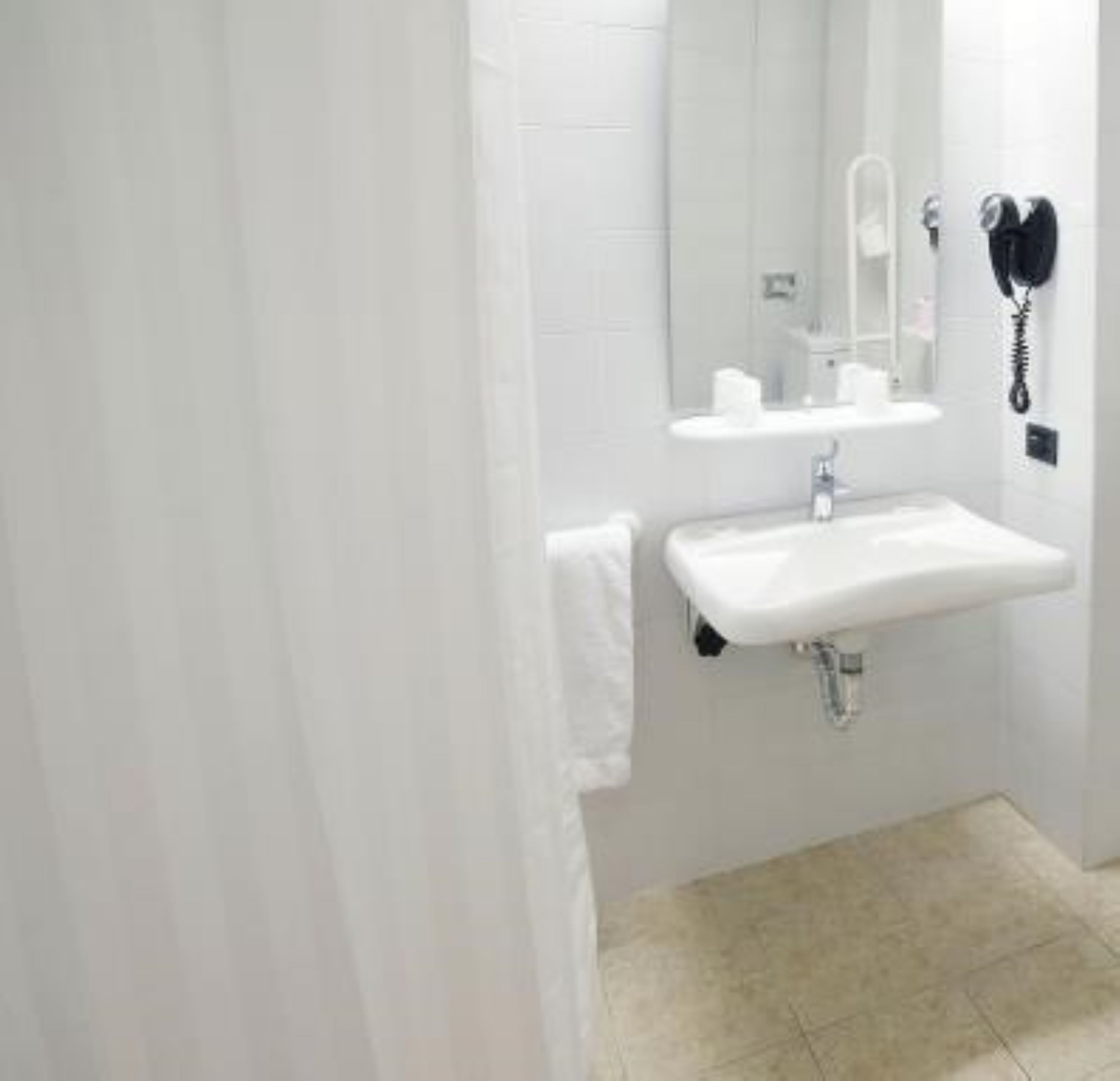 A bathroom with a white sink, mirror, and a hairdryer mounted on the wall.
