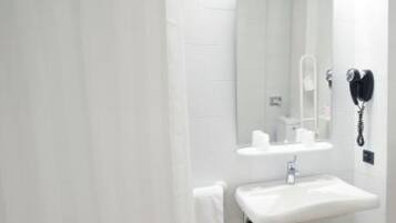 A bathroom with a white sink, mirror, and a hairdryer mounted on the wall.