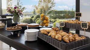 Un bufé con pasteles, frutas y vistas a un jardín paisajístico.