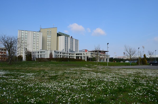 A modern hotel with a flat roof and a large garden area with white flowers.