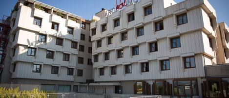 A multi-story hotel with a swimming pool in the foreground.
