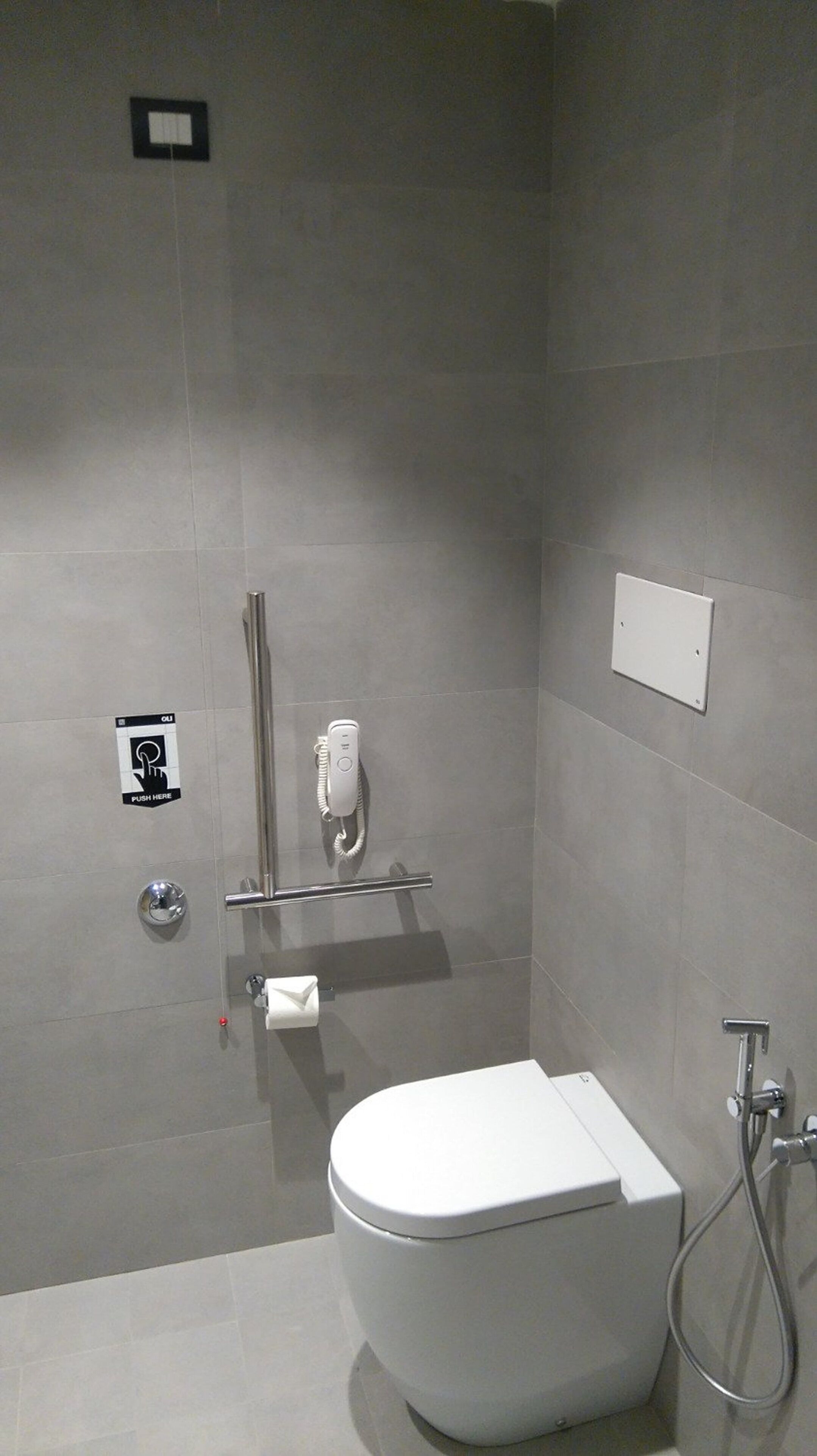 Une salle de bain moderne équipée de toilettes, d’un sèche-mains, d’un porte-serviettes et d’une douche.