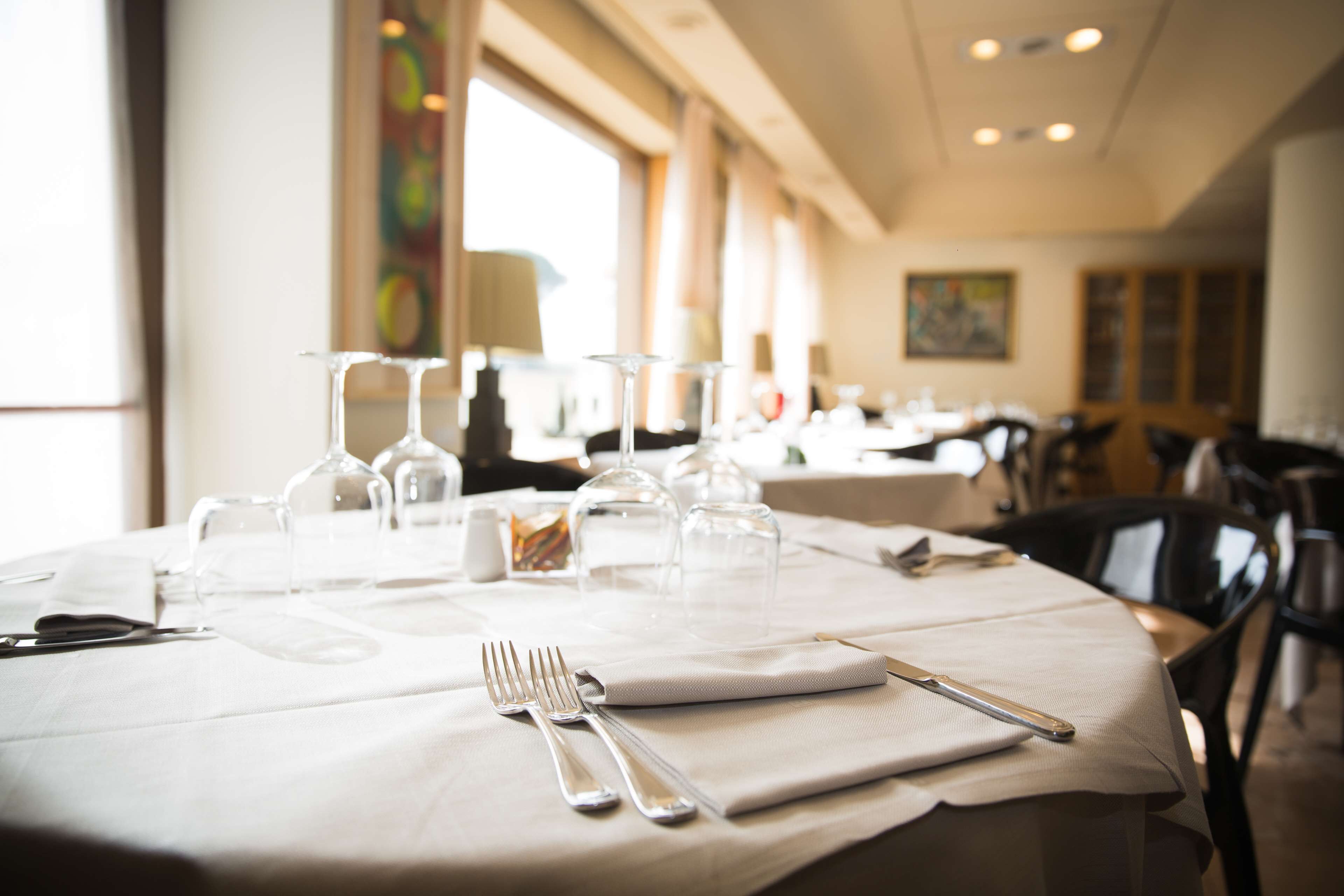A dining table set with cutlery and wine glasses, with a view of the restaurant interior.