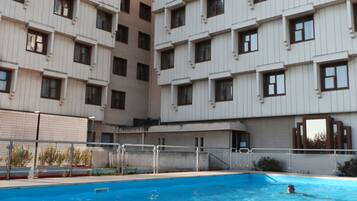 Una piscina al aire libre de temporada, sombrillas