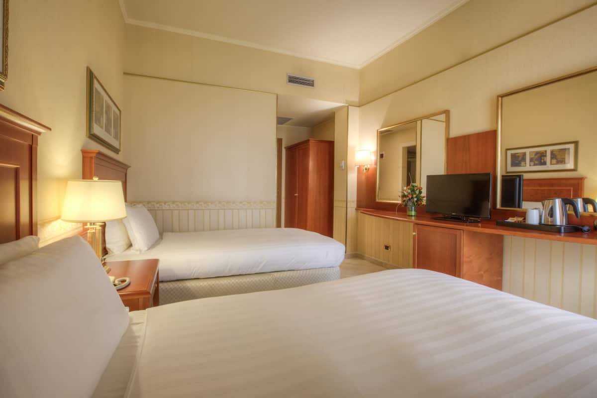 Une chambre d’hôtel avec deux lits, une télévision, une machine à café et un miroir.