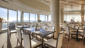 Un comedor espacioso con techos altos, ventanas grandes y vista al océano.
