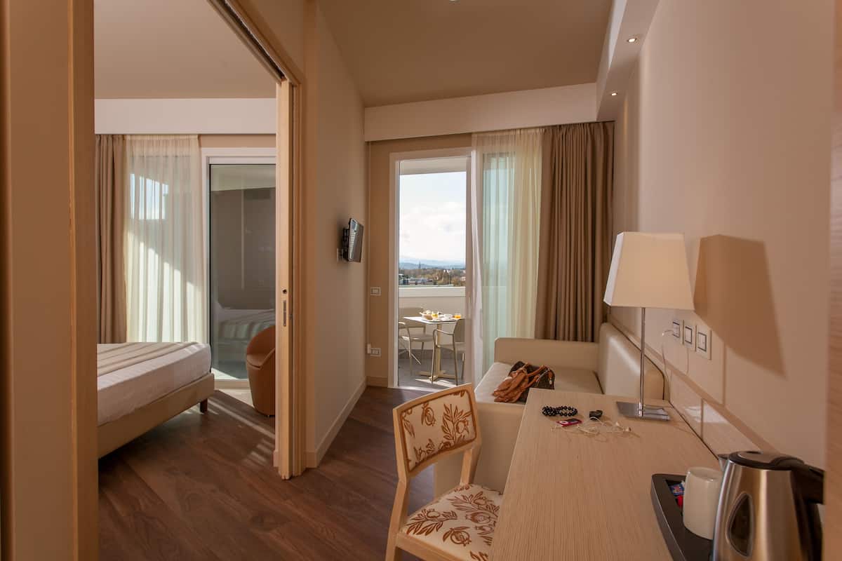 Une chambre d’hôtel comprenant un lit, un coin repas avec une table et des chaises, un canapé et une vue sur la ville par la fenêtre.