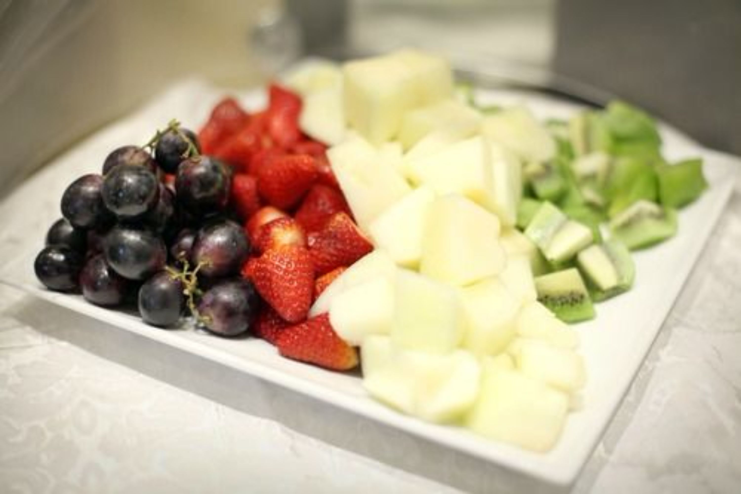 A plate of assorted fruits including grapes, strawberries, and diced apples and kiwi.