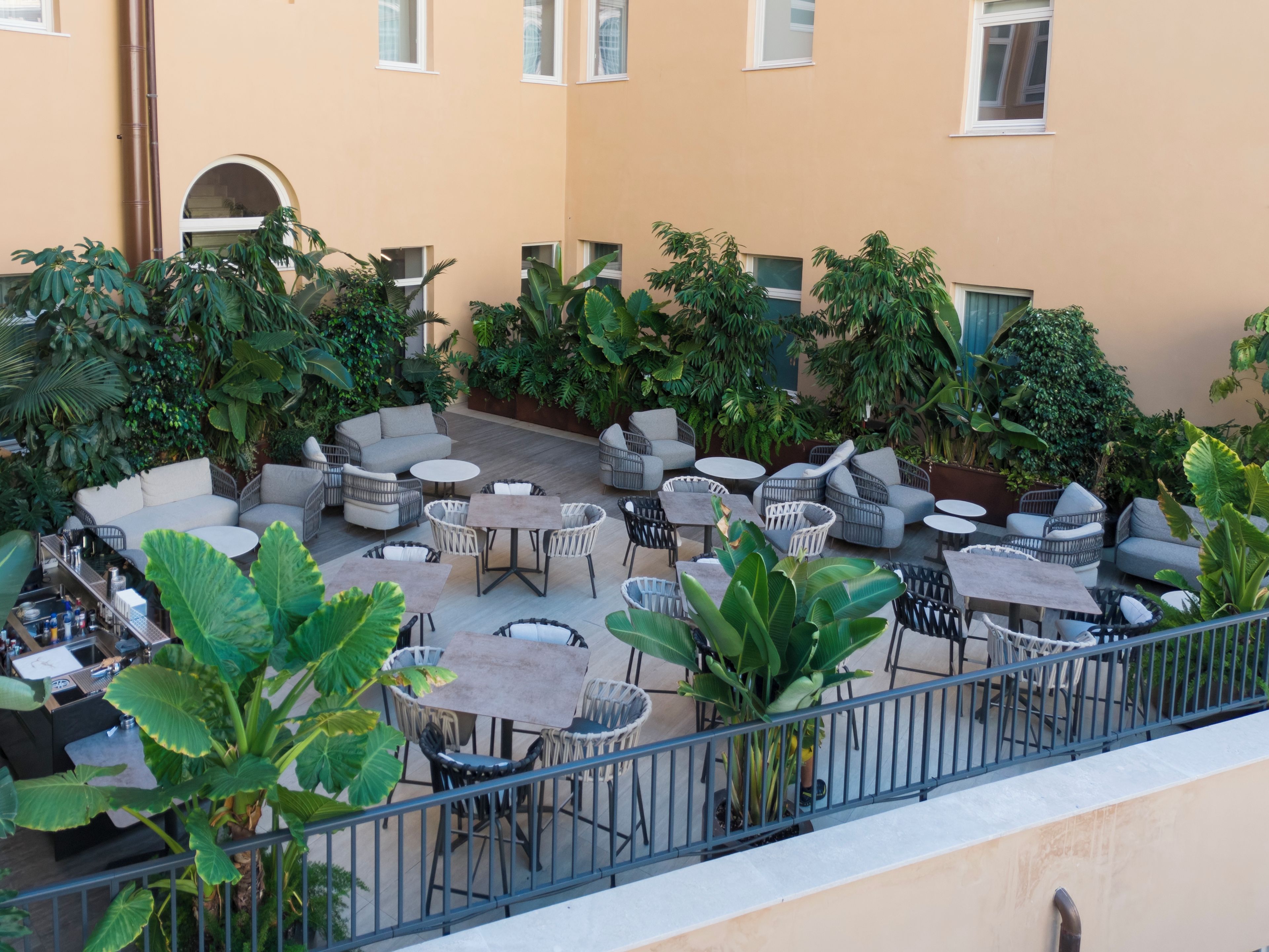 Una terrazza esterna con diverse zone relax, tra cui divani e tavoli, circondata da vegetazione lussureggiante.