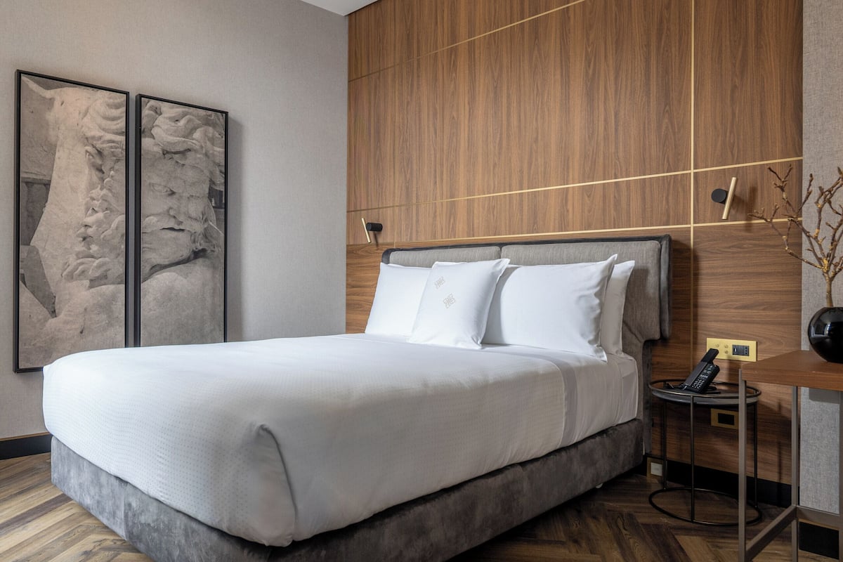 Una moderna camera d'albergo con un letto grande, parete rivestita in legno e pavimento in legno a spina di pesce.