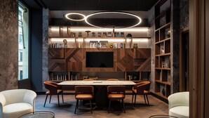 A modern conference room with a large table, six chairs, a flat-screen TV, and bookshelves. - Palazzo 4 Fontane 12 (Rome)