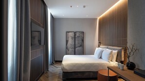 A modern bedroom with a large bed, a wooden desk, and a view of the city. - Palazzo 4 Fontane 12 (Rome)
