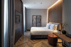 Un dormitorio moderno con una cama grande, un escritorio de madera y vistas a la ciudad.