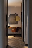 Un interior moderno con suelo de madera, un escritorio con una silla y un televisor fijado a la pared.