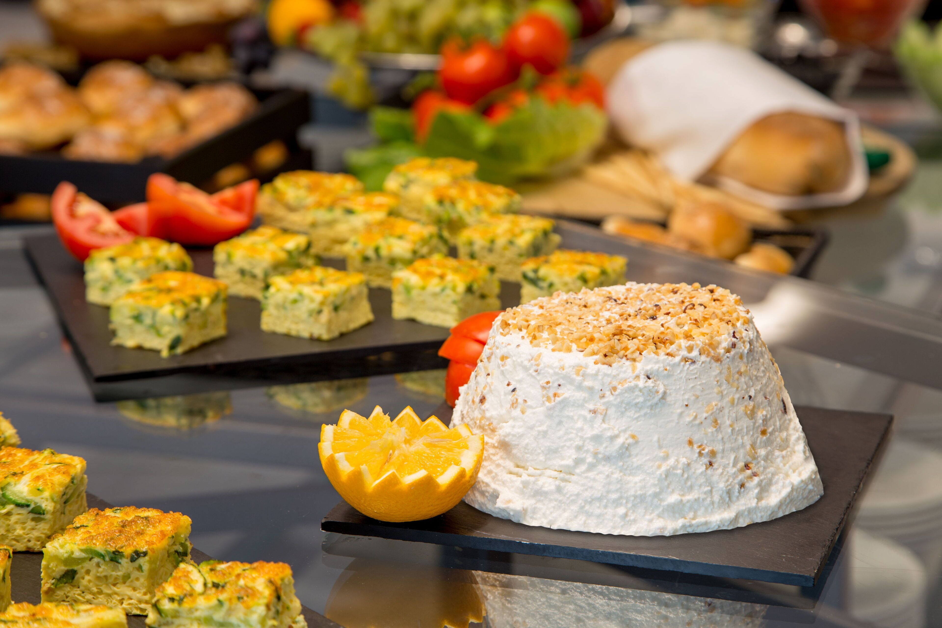 A buffet table with various food items including a large cake on a black square board.