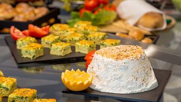 A buffet table with various food items including a large cake on a black square board.