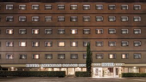 A multi-story hotel with a uniform facade, featuring a series of windows and a central entrance. - Hotel American Palace Eur (Rome)
