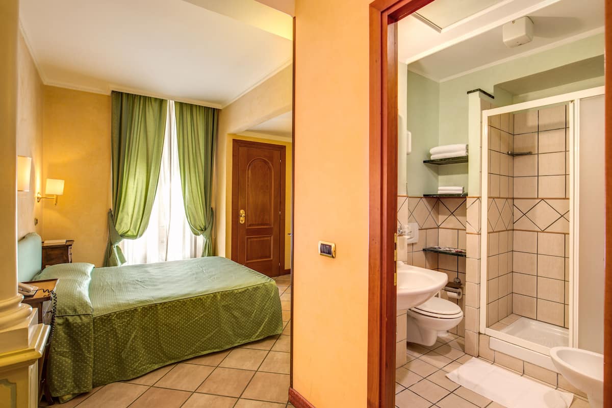 A hotel room with a bed, a bathroom with a shower, toilet, and sink.