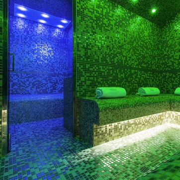 A room with mosaic tile walls and a bench with towels.
