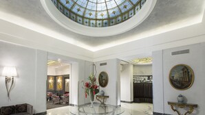 A spacious lobby with a glass table, a sofa, and a vase with flowers. - Hotel Artemide (Rome)